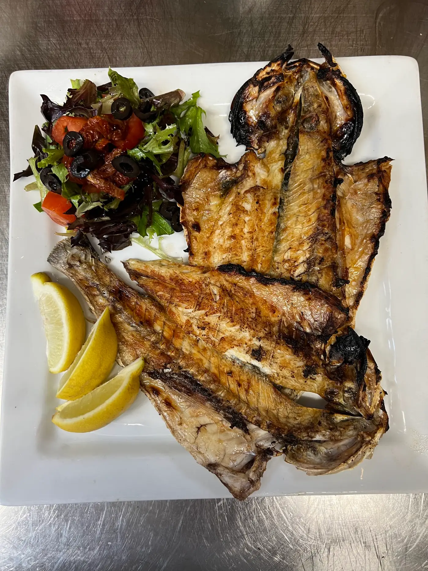 Grilled whole fish on a plate in a professional kitchen